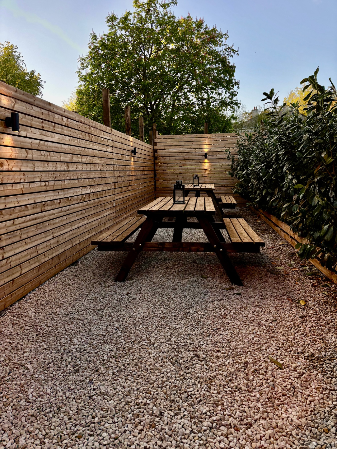 Lantern-lit timber benches on the gravel rest deck at The Hive